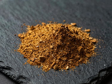 Fine golden-brown wood powder poured onto a dark slate surface, macro detail showing consistent fine grain and dry texture