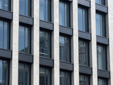 Abstract architectural details of a financial center, reflecting clean lines, bright natural office light, deep navy and slate tones, sharp focus, 35mm architectural lens