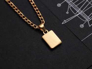 Overhead flat-lay of gold chain links and pendants next to a technical drawing on black paper, sharp metallic textures