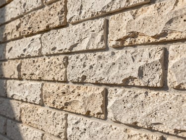 Close-up 45-degree angle shot of manufactured stone veneer wall installation in Florida afternoon sun — mortar joints tight and consistent, shadow depth showing stone relief, no people, no text