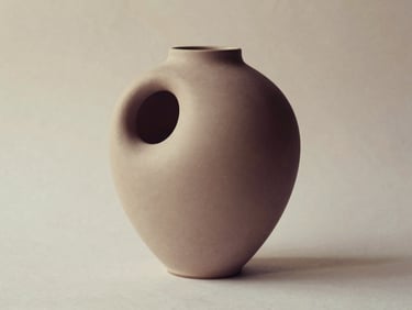Modernist ceramic vase with an organic, pebble-like form, matte finish, soft shadows, minimalist aesthetic