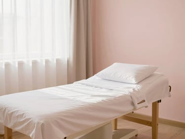 Clean, serene studio suite interior with soft natural daylight, minimalist decor, comfortable treatment bed, warm gold and soft pink tones, no people.