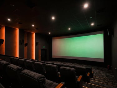 Wide-angle architectural view of a finished luxury home cinema, dramatic low-key theater lighting, deep black shadows with orange accent glows, 35mm