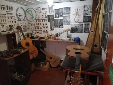 Taller de luthería con diversos instrumentos de cuerda, herramientas, moldería e imágenes en pared