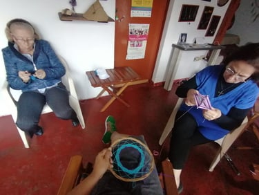 personas tejiendo juntas en costurero, en una sala con puertas de madera y elementos artesanales