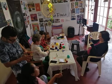 Personas en un taller de mandalas tejidas tipo ojos de dios en sala de casa cultural en Manizales