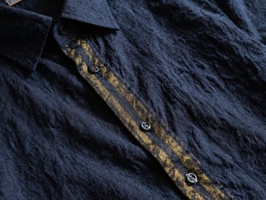 Close-up of fine linen weave on a relaxed-fit shirt, dramatic side lighting, rich textures