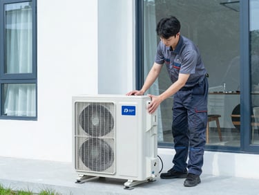 Professional technician finishing the clean installation of a premium outdoor heat pump unit next to a modern house.