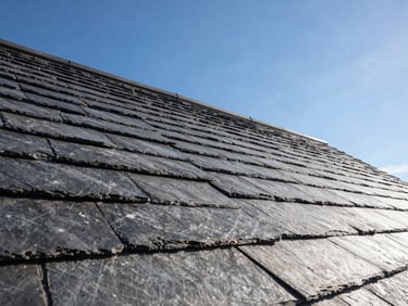 Wide angle of a perfectly finished slate roofline against a clear blue UK sky, clean straight lines, professional craftsmanship.
