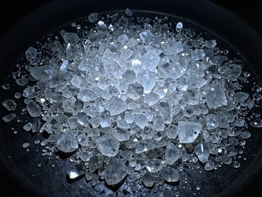 Close-up of clear, crystalline quartz fragments on a dark industrial surface, high-contrast cool daylight, deep blue and slate tones, sharp details, wide-angle lens