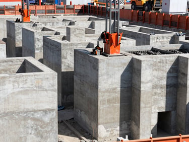 Industrial documentary photography of heavy civil upgrading works, massive concrete foundations being poured under high-contrast daylight