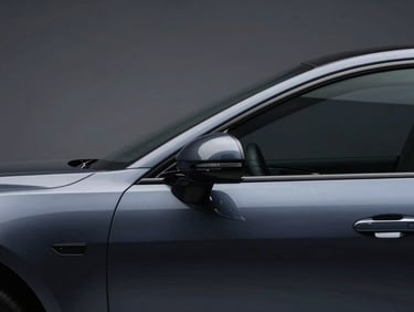 Elegant close-up of a polished dark metallic car silhouette under soft studio lighting, highlighting clean curves and premium craftsmanship.