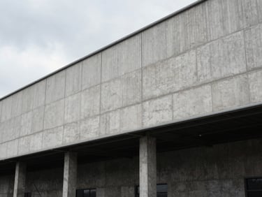 Architectural view of a modern industrial warehouse facade, concrete panels, precise construction, overcast daylight.