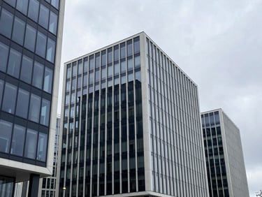Wide-angle architectural view of modern glass business centers in Vilnius under a cool overcast sky, sharp geometric concrete lines, 35mm minimalist corporate photography