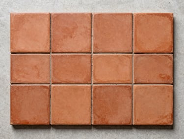 Overhead product flatlay of terracotta-body ceramic tiles under cool studio light, revealing warm red cross-section against a pale concrete surface, precise arrangement, no people