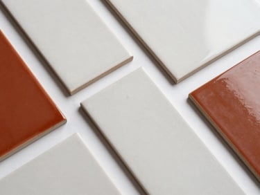 Overhead product flatlay of ceramic tile samples in pasta blanca and pasta roja finishes arranged on a white surface, studio strobe lighting, sharp material detail visible on each piece