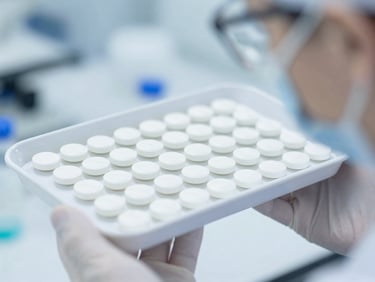 Macro close-up of a scientist in a cleanroom suit inspecting a tray of freshly pressed tablets, sharp macro focus, bright high-key laboratory lighting, sterile white and cool blue tones