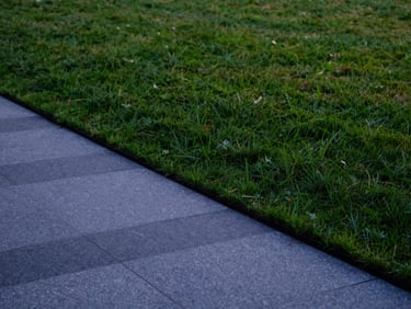 A clean, sharp shot of a neatly edged lawn meeting a structured stone pathway, twilight lighting showing crisp details, 35mm lens