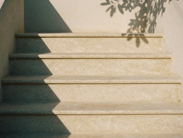 Close-up of a minimalist stone staircase with exactly three steps, warm afternoon sunlight casting soft shadows, 35mm