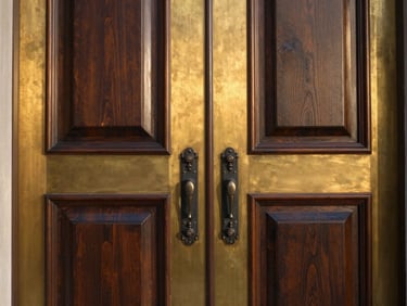 Close-up of premium brass and dark wood finishes on a grand entrance door of a luxury estate, golden-hour light, editorial architectural photography.