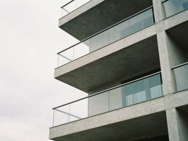 Architectural detail of a modern concrete and glass apartment balcony, overcast sky, minimalist framing, 35mm film.