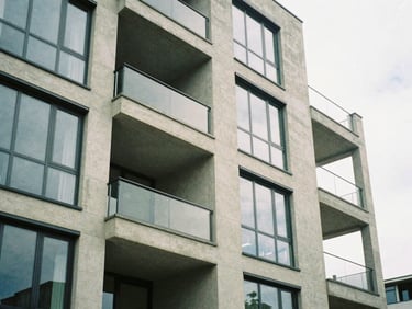Architectural detail of a modern concrete and glass apartment building, soft overcast daylight, muted natural tones, 35mm film