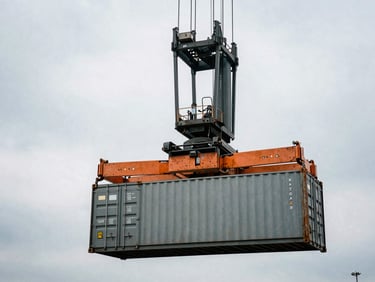 A massive reach stacker lifting a shipping container in an active port terminal, overcast sky, industrial safety orange accents, 35mm film grain