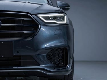 Flawless invisible tuck technique on the complex curves of a luxury SUV bumper, clean dust-free application bay background, cool key lights, 35mm