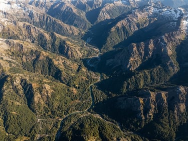 Extreme wide-angle aerial orthophoto of a rugged Chilean Andean valley at sunrise, sharp topographic contours, crisp morning sunlight, deep forest green and earth tones, 35mm lens