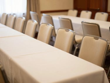 Polished corporate event setup with neat rows of modern chairs, clean table lines, and soft warm background lighting, 35mm photography