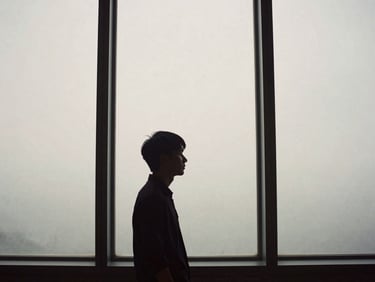 Contemplative fine art photography of Guto's silhouette near a tall concrete window, soft diffused afternoon light, desaturated earth tones, 35mm film