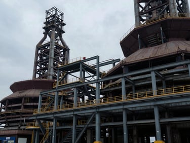 Wide environmental shot of architectural geometry in heavy industry, structural steel framework, overcast daylight, cool low-key lighting.