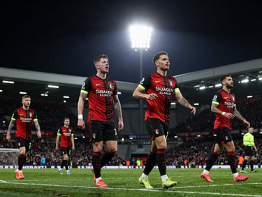 Action shot of AFC Bournemouth players celebrating a goal on the pitch, dramatic stadium floodlights, dynamic sports photography