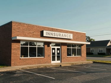Exterior of a modest single-story insurance agency office building in Murfreesboro on a clear afternoon, a small parking lot in the foreground, warm brick facade, office signage visible, quiet neighborhood street to the right side, natural daylight