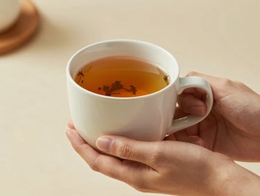A hand holding a warm ceramic mug filled with herbal tea, soft natural lighting, elegant minimalist aesthetic, peaceful tone.