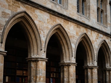 Architectural detail of a historic university campus, gothic arches, warm directional light, deep navy and champagne tones, shallow depth of field.