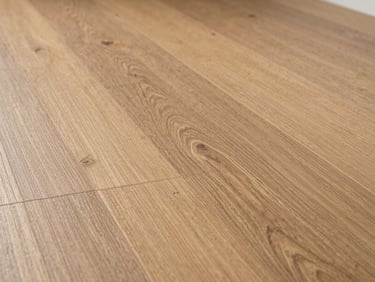 Close-up of premium wide-plank oak flooring, matte finish, highlighting natural wood grain under soft daylight.