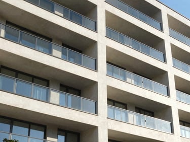 Bright architectural detail of a modern residential building facade, clean concrete and glass, sunny daylight, high contrast