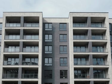 Symmetrical architectural shot of a modern multi-unit residential building with crisp concrete lines under cool, overcast daylight.