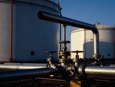 Industrial storage terminal with steel pipelines and valves under crisp daylight, high contrast.