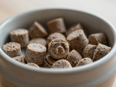 Close-up of small, natural gourmet dog training treats in an open ceramic jar, shallow depth of field, soft light.