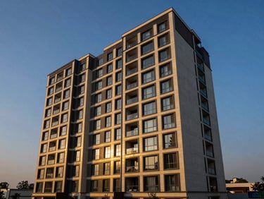 High-angle architectural exterior of a modern luxury apartment building in Gurugram at dramatic twilight, deep blues and warm gold accents, wide-angle lens, sharp focus