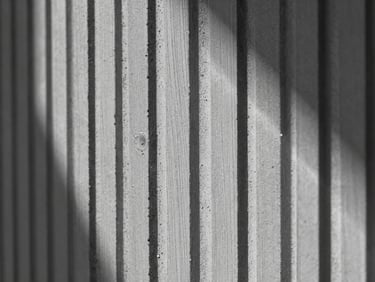 Extreme close-up of cured board-formed concrete texture, vertical wood grain lines, high-contrast raking light, sharp architectural detail