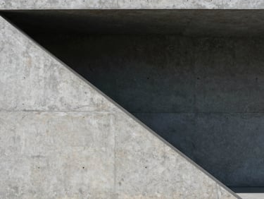 Architectural concrete structure with sharp geometric shadows, cool daylight, minimalist composition
