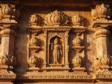 Close view of an ornate Rajasthani temple wall at golden hour — carved sandstone relief of lotus and geometric patterns, warm amber light raking across the surface, deep shadows in the recesses, no people in frame