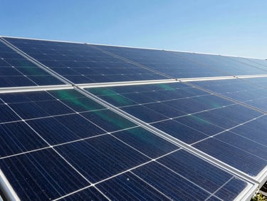 Close-up of a high-efficiency solar panel surface reflecting a clear blue sky, bright daylight, sharp shadows, deep blue and emerald tones, wide-angle lens, high-end commercial aesthetic