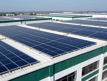Wide architectural shot of a large commercial building with extensive solar panels on its roof, clean lines, high-contrast lighting, deep blue tones.