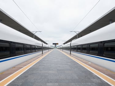 A clean architectural view of a modern train platform connecting directly to an airport terminal corridor, bright overcast light, slate grey tones.
