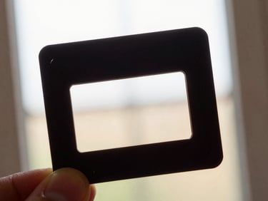 Close-up of a vintage 35mm slide held against a lightbox, showing intricate details, warm natural light.