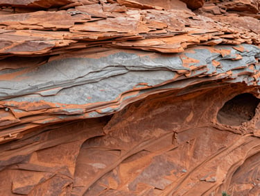 Macro shot of weathered Utah sandstone showing stratified layers of orange clay and grey silt, high-contrast natural light.